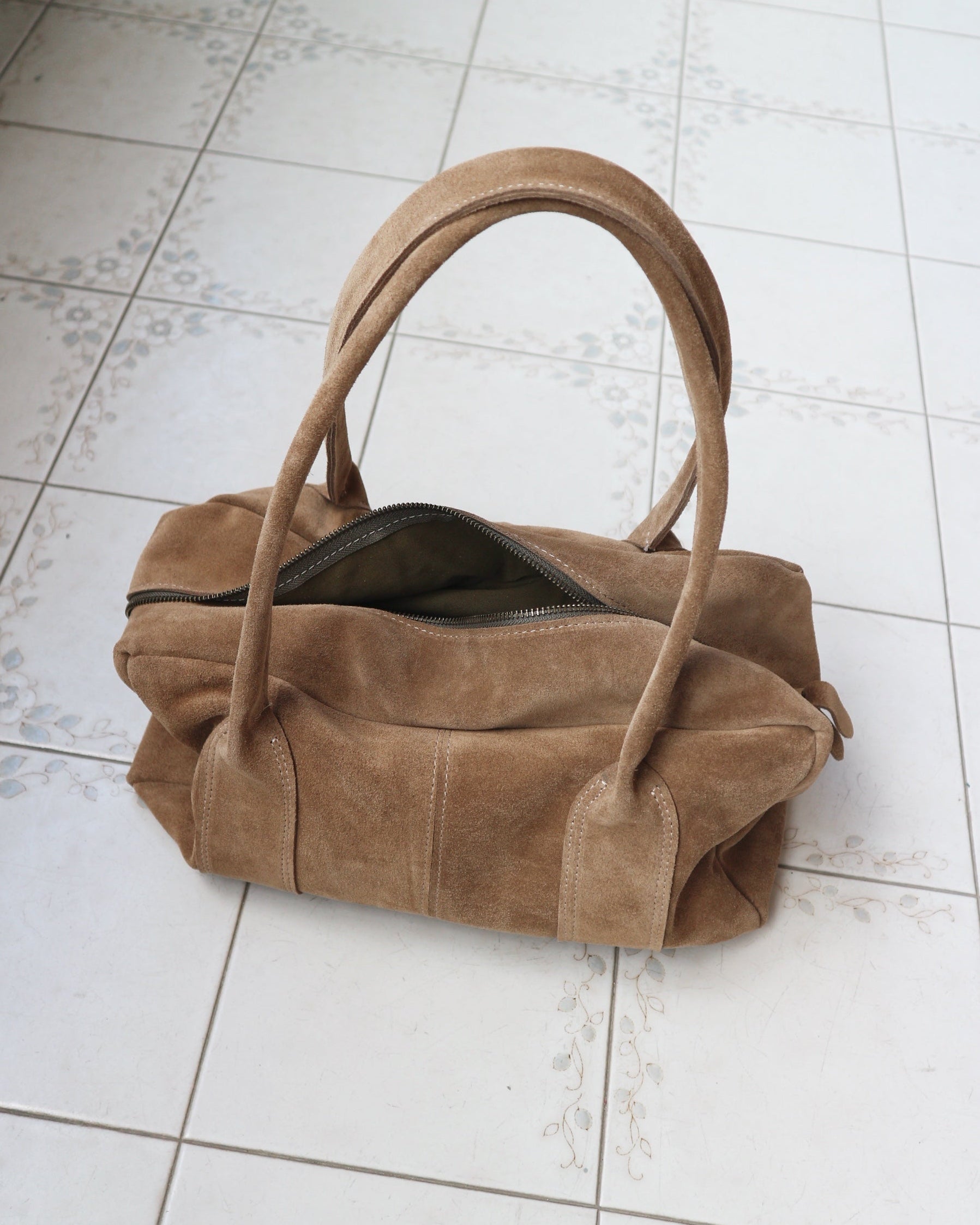 Brown suede handbag on a tiled floor