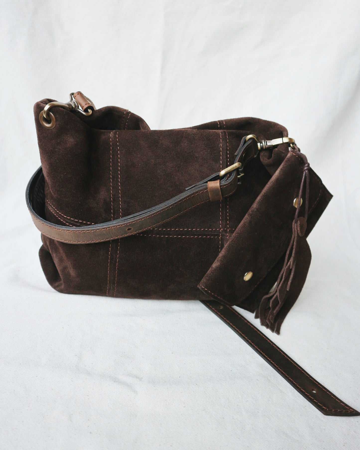 Brown suede handbag with a strap and charm for keys