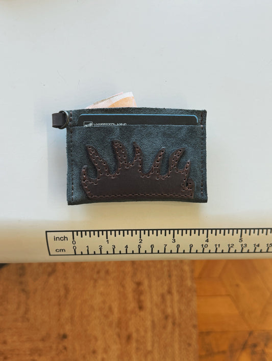 Small leather cardholder with deer antler design on a white surface with a ruler for scale.