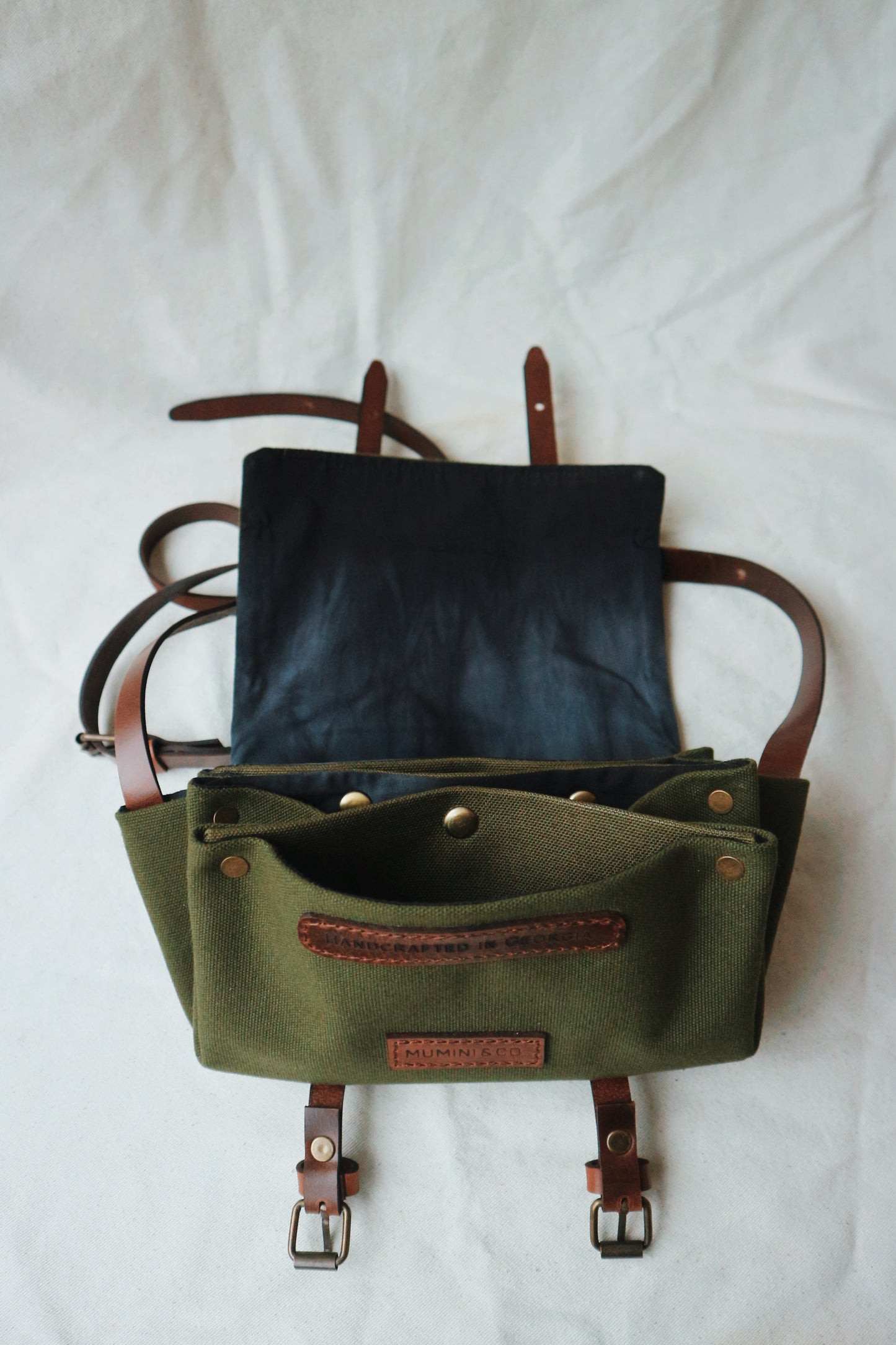 Green leather bag with brown straps on a white background