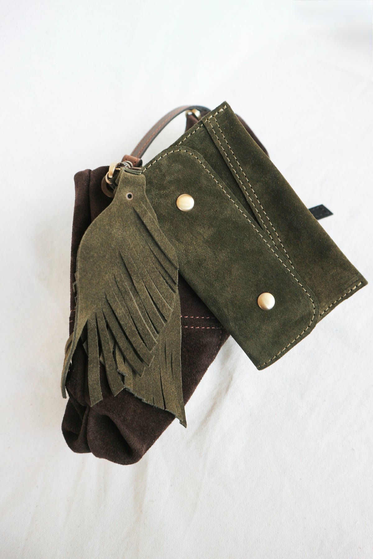 Green suede wallet with fringes and buttons on a white background