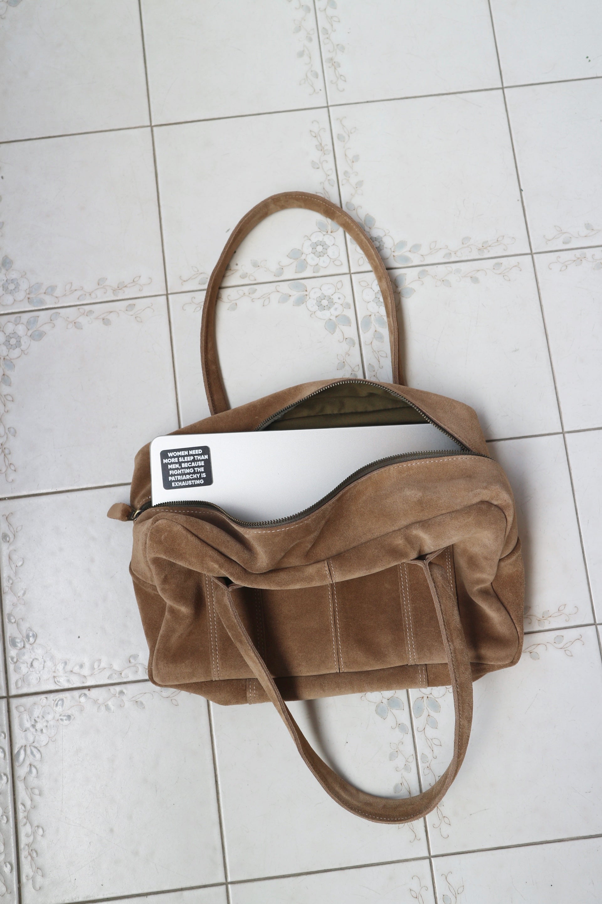 Brown suede handbag on a tiled floor