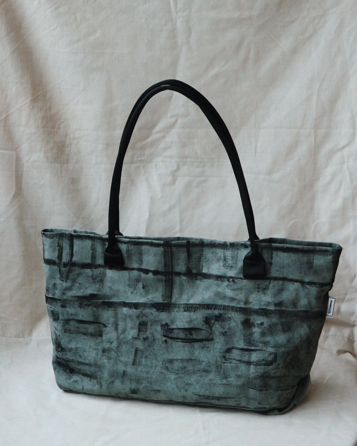 Green textured handbag on a white cloth with a neutral background